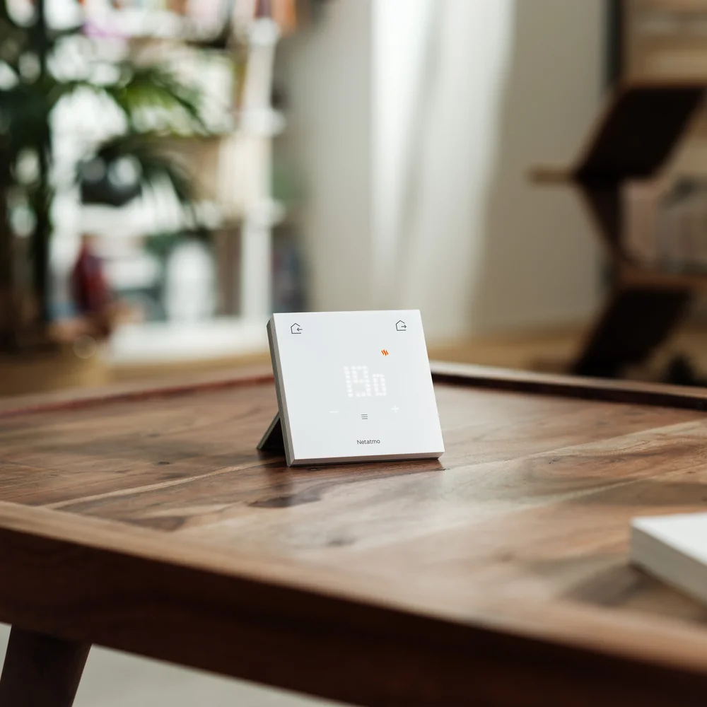 Le Thermostat ORIGINAL posé sur son socle, sur une table basse en bois
