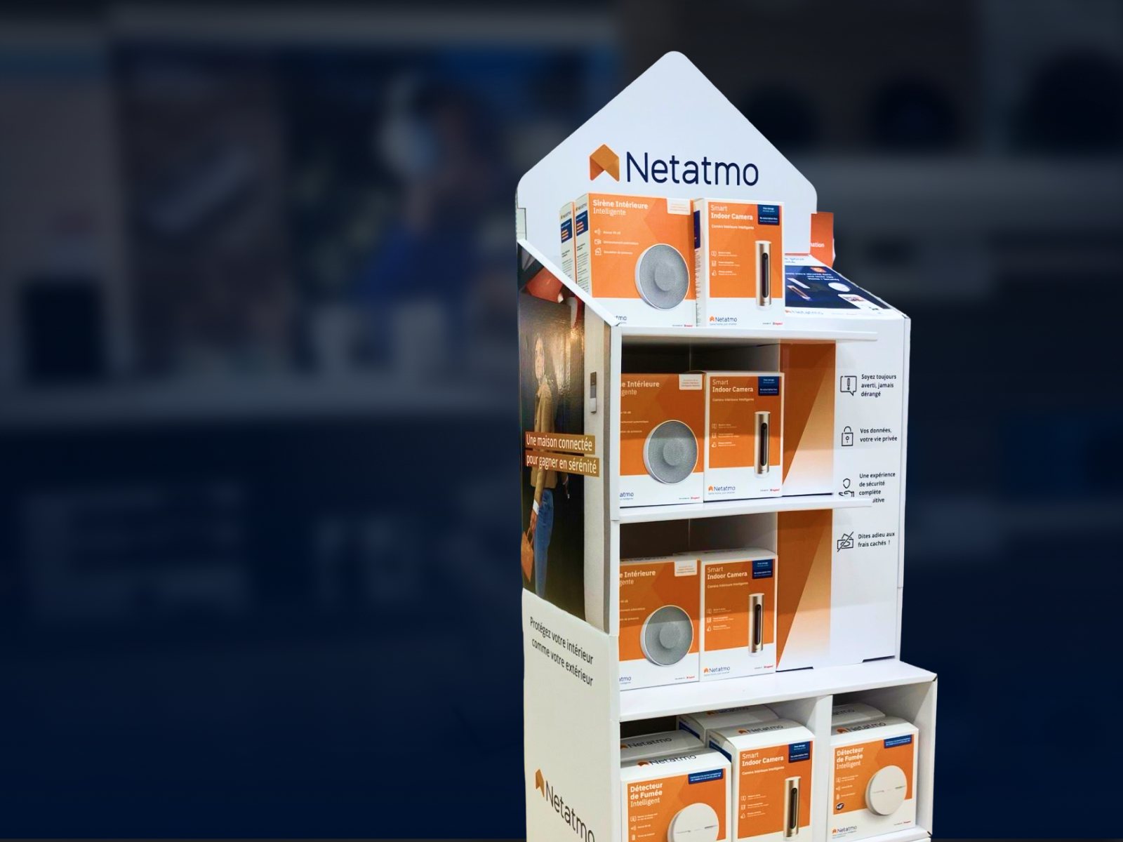 The Netatmo in-store display stand, filled with packagings, in front of blurred store shelves